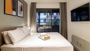 A hotel room with a bed, a TV, a balcony with a view, and artwork on the wall. - Think Home Vila Madalena (São Paulo)