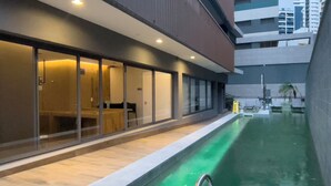 A modern hotel interior with a swimming pool, glass doors, and a view of the cityscape. - Think Home Vila Madalena (São Paulo)