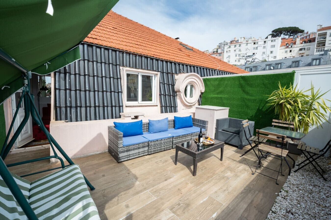 Une terrasse sur le toit aménagée avec un canapé, une table, des chaises et un pot de fleurs.