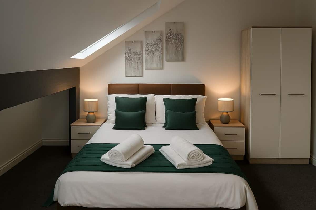 A hotel room with a bed, two nightstands, a wardrobe, and a skylight.