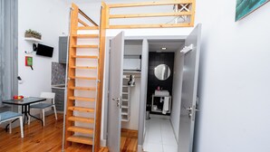 Un espace de vie compact comprenant un lit en mezzanine, un coin repas et une kitchenette.