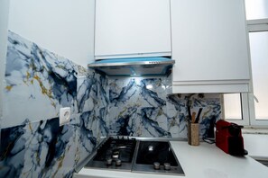 A kitchen with a gas stove, a built-in oven, a marble backsplash, and white cabinetry. - Large 3-Bedroom 2-bathroom 1-Livingroom 2-double bed 2-Twin Bed Apartment (Lisbon)