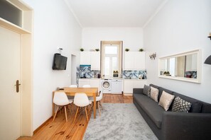 A compact living space with a dining area, kitchenette, and a sofa. - Large 3-Bedroom 2-bathroom 1-Livingroom 2-double bed 2-Twin Bed Apartment (Lisbon)