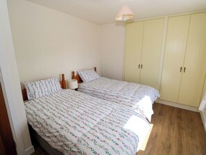 A bedroom with two beds, a wardrobe, and a ceiling lamp. - Cahir Cottage (Ballinrobe)