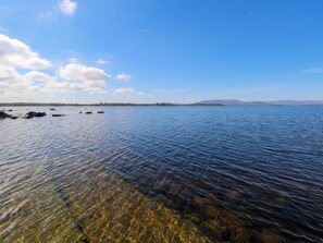 A calm lake with clear water, distant mountains, and a clear sky. - Cahir Cottage (Ballinrobe)