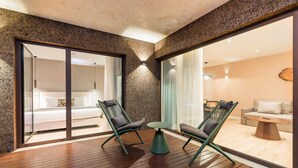 A modern room with a wooden floor, two green chairs, a small round table, and a glass door leading to a bedroom. - Haven Nature Villa II by Feel Discovery (Batalha)