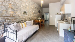 A cozy room with a stone wall, a bed, a dining table, and a kitchenette. - Beachfront Mani Luxury Stone Nest, Steps from Sea (Kokkala)