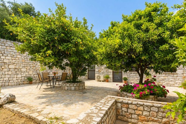 An outdoor patio with stone walls, a table with chairs, and potted plants.