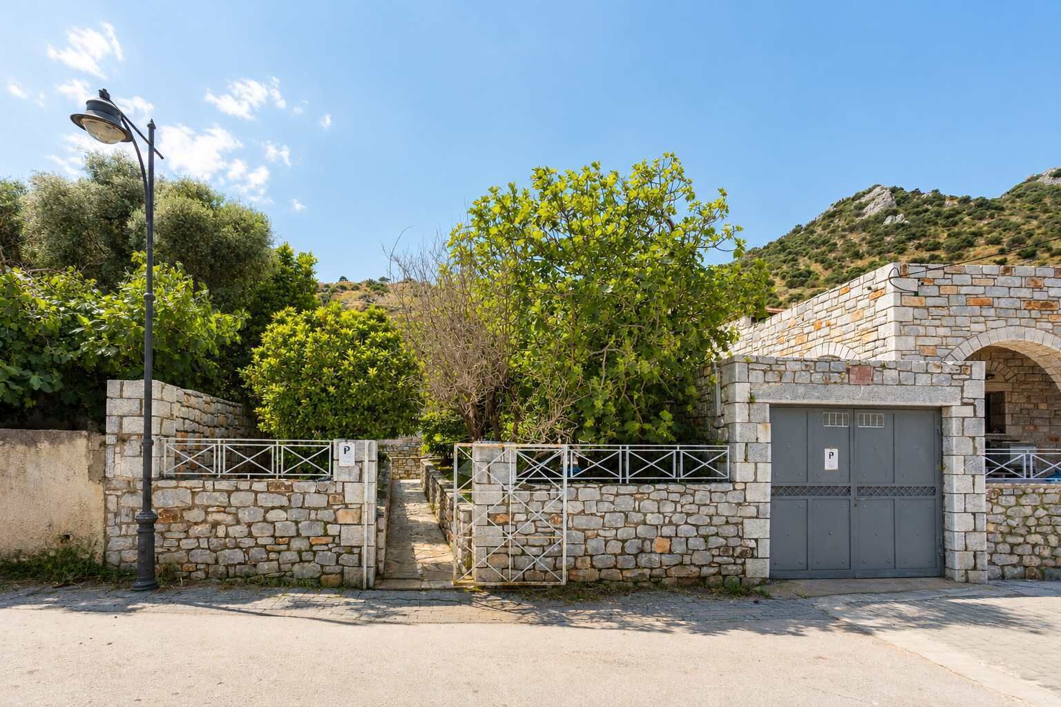A stone building with a gated entrance, a street lamp, and a clear sky.