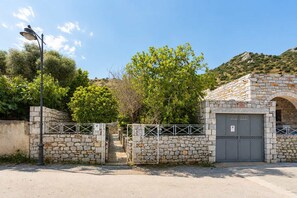 A stone building with a gated entrance, a street lamp, and a clear sky.