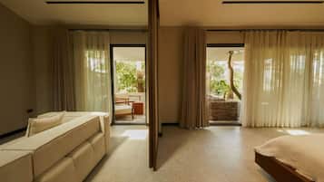 Une chambre d’hôtel moderne, dotée d’un canapé, d’un lit et offrant une vue sur un balcon aménagé avec du mobilier d’extérieur.