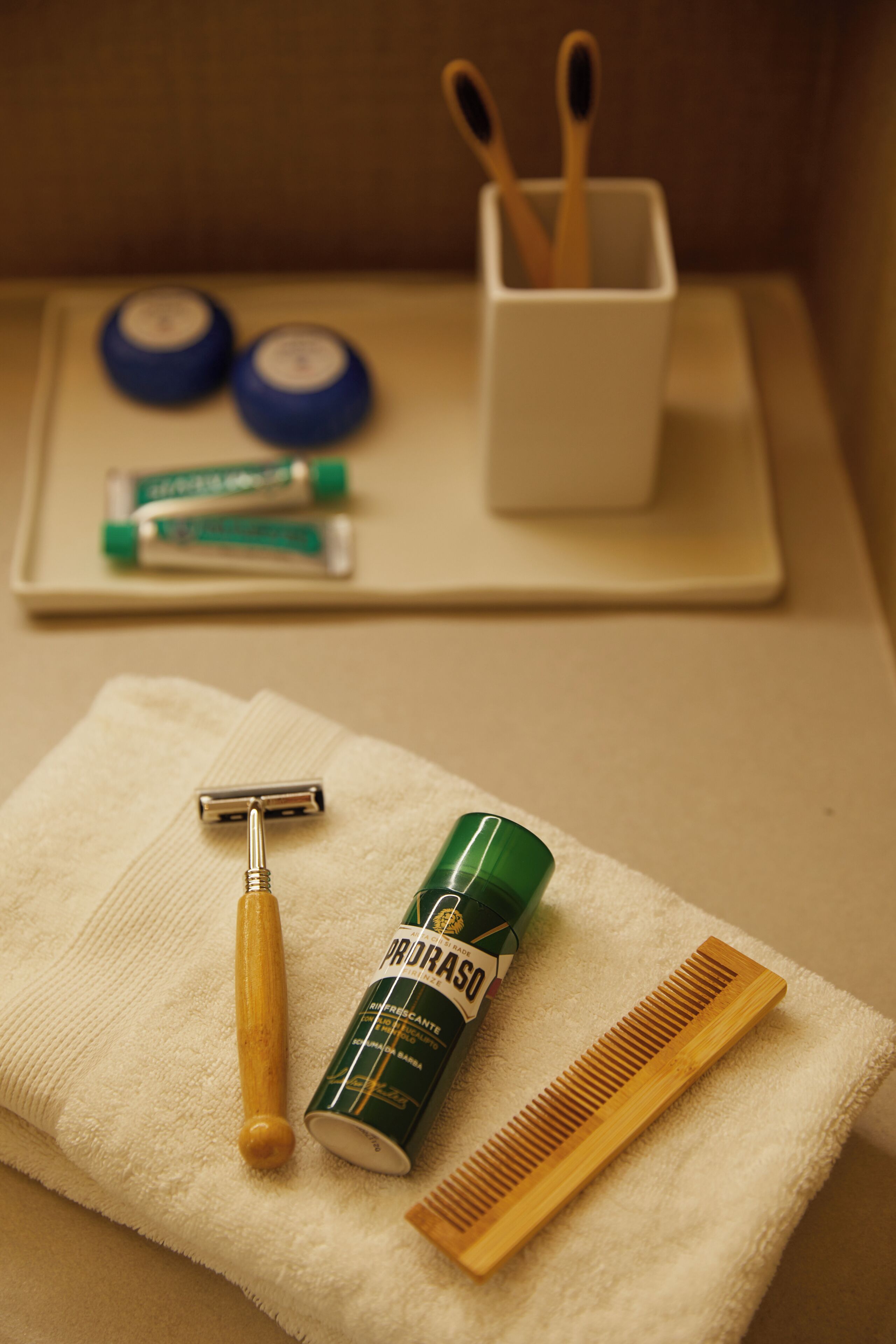 A bathroom with a towel, razor, comb, and toiletries on a tray.