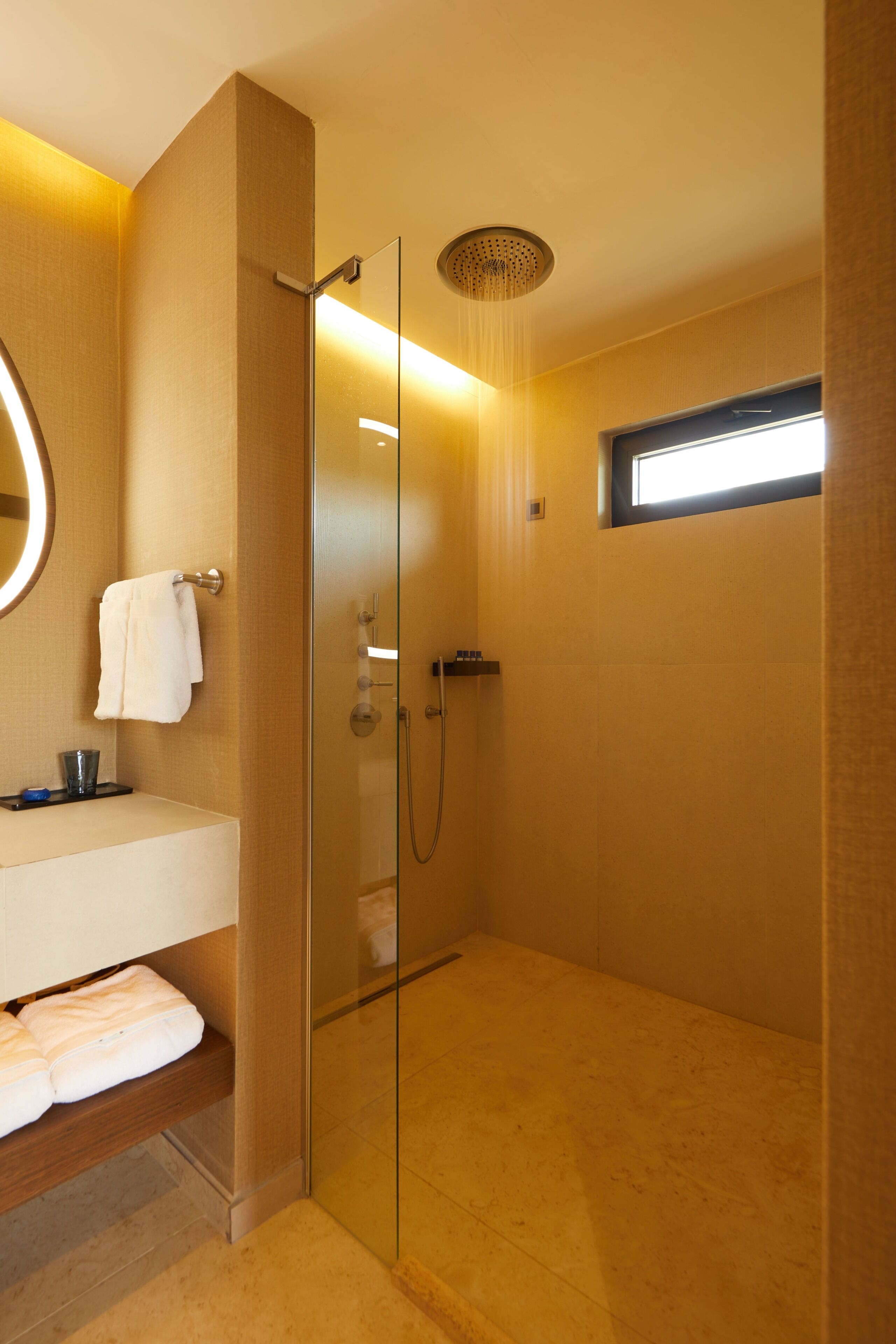 A modern bathroom with a glass-enclosed shower, a vanity with a mirror, and a towel rack.