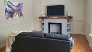 Ein Wohnzimmer mit Kamin, einem flachbildfernseher darüber montiert und einem farbenfrohen abstrakten Gemälde an der Wand.