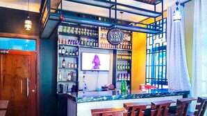 A bar area with a counter, bar stools, shelves of bottles, and a sign that says 'LOVE YOU MORE'. - RIVANA HOTEL GOBA (Dar es Salaam)