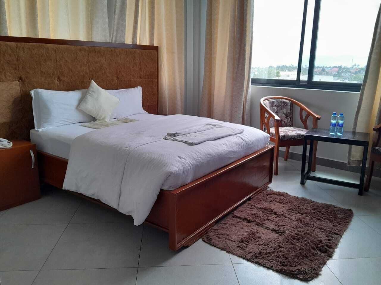 Une chambre d’hôtel avec un lit, une table de chevet, une chaise, une table et une vue par la fenêtre.