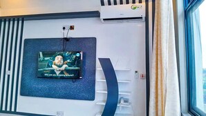 A modern hotel room with a mounted television, air conditioning unit, and a phone on a wall. - RIVANA HOTEL GOBA (Dar es Salaam)