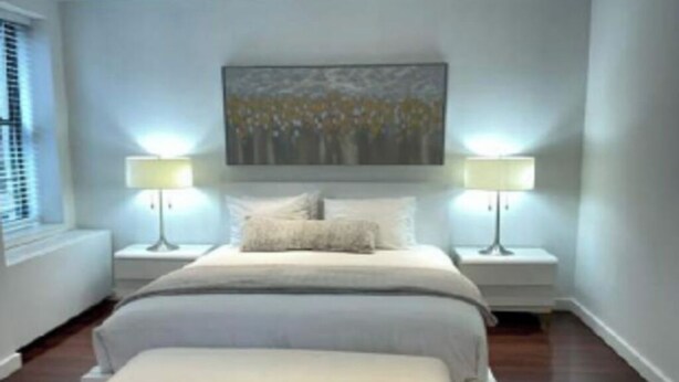 A bedroom with a bed, two bedside tables, a nightstand, a bench, and a painting on the wall.