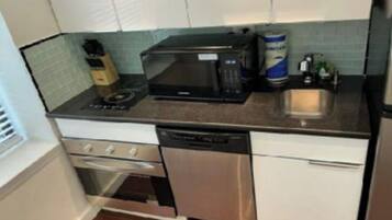 A kitchen with a microwave, stove, dishwasher, and a sink.
