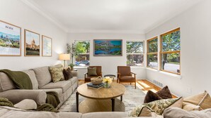 A living room with a sofa, armchairs, a coffee table, and framed pictures on the walls. - Steps to Downtown The North End Gem (Boise)