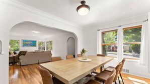 A dining area with a wooden table and chairs, a sofa, and a painting on the wall. - Steps to Downtown The North End Gem (Boise)