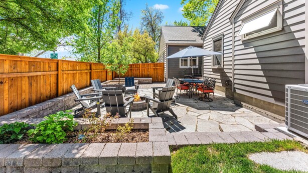 A backyard patio with outdoor furniture, a fire pit, and a wooden fence. - Steps to Downtown The North End Gem (Boise)