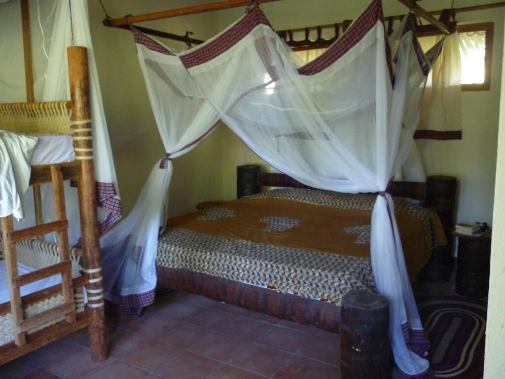 A bed with a canopy, a wooden chair, and a small table.