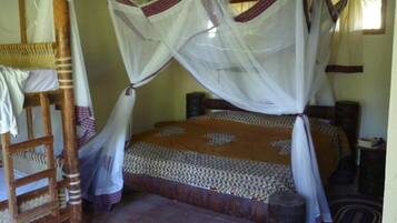 A bed with a canopy, a wooden chair, and a small table.