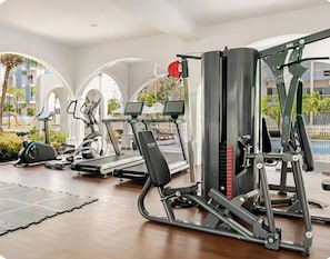 Uma academia com esteiras, remo e um banco de musculação.