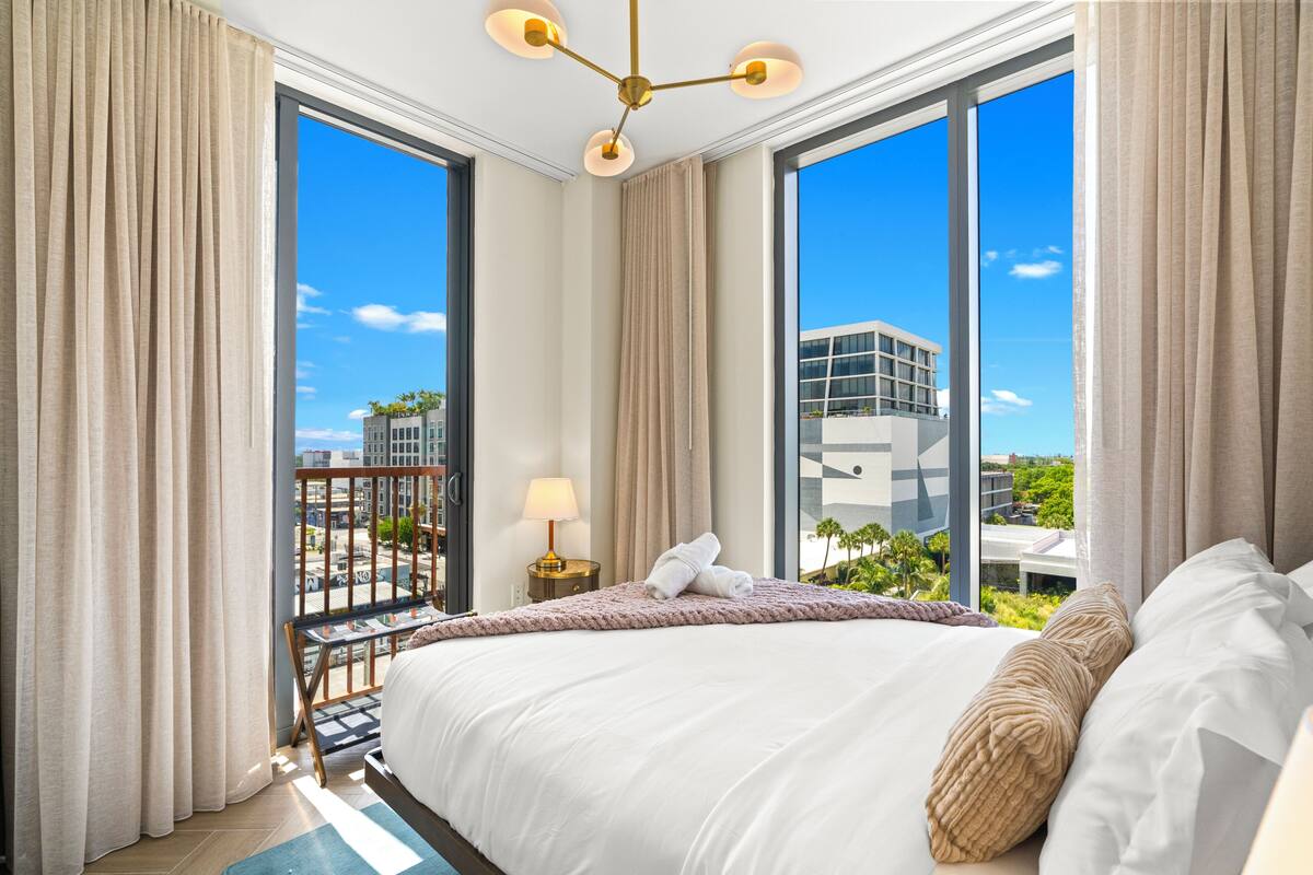 Habitación de hotel con una cama grande, vistas de la ciudad y un balcón con barandilla.