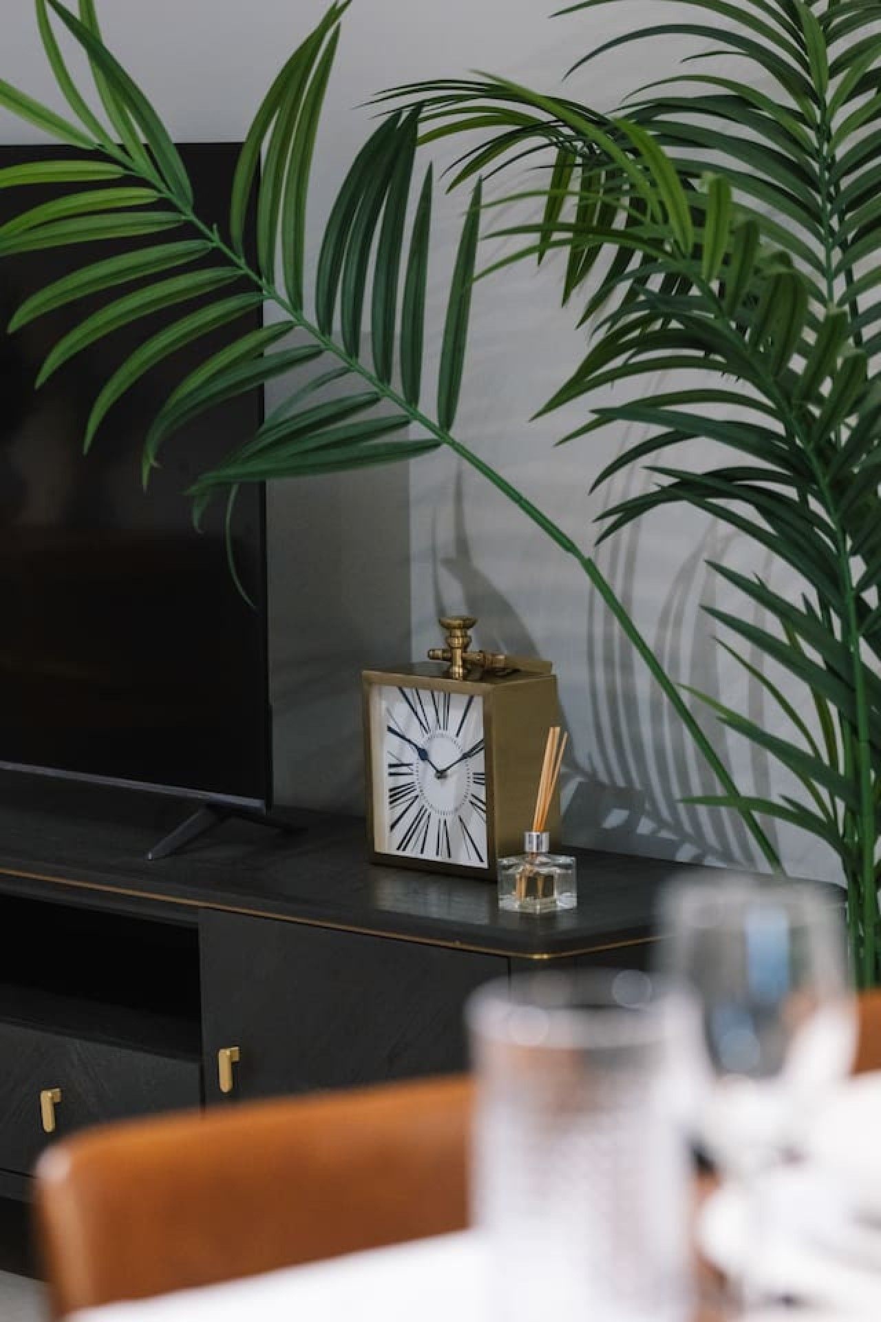 Un soggiorno moderno con una televisione a schermo piatto, una sveglia decorativa e una pianta in vaso.