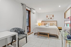 Un dormitorio con cama, mesita de noche, silla y televisor.