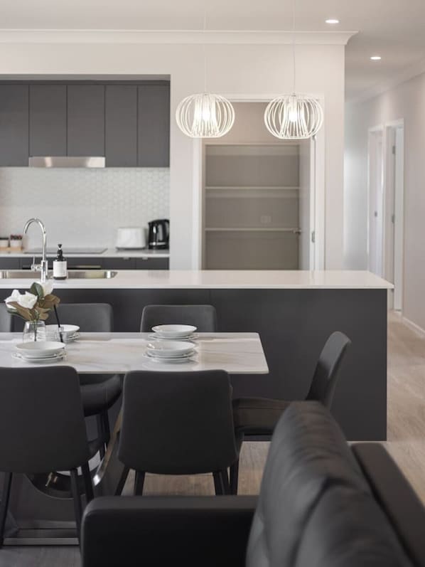 A modern kitchen with a central island, dark cabinetry, and pendant lighting.