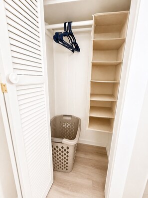 A closet with white walls, a wooden floor, and a hanging rack with clothes. - Condo walking distance to Coligny Beach, Shops & Dining. Your Hilton Head Haven! (Hilton Head Island)