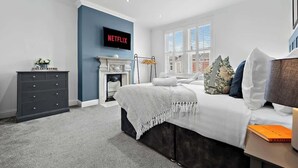 A bedroom with a bed, a dresser, a fireplace, a TV, and a window. - Charming Portsmouth Home w/ Private Garden (Portsmouth)