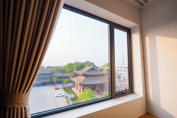 A room with a large window overlooking a traditional building and a parking lot.