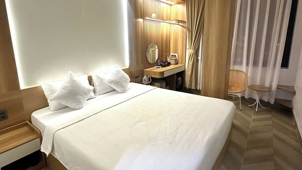 Ett modernt hotellrum med en stor säng, ett skrivbord, en stol och ett badrum.