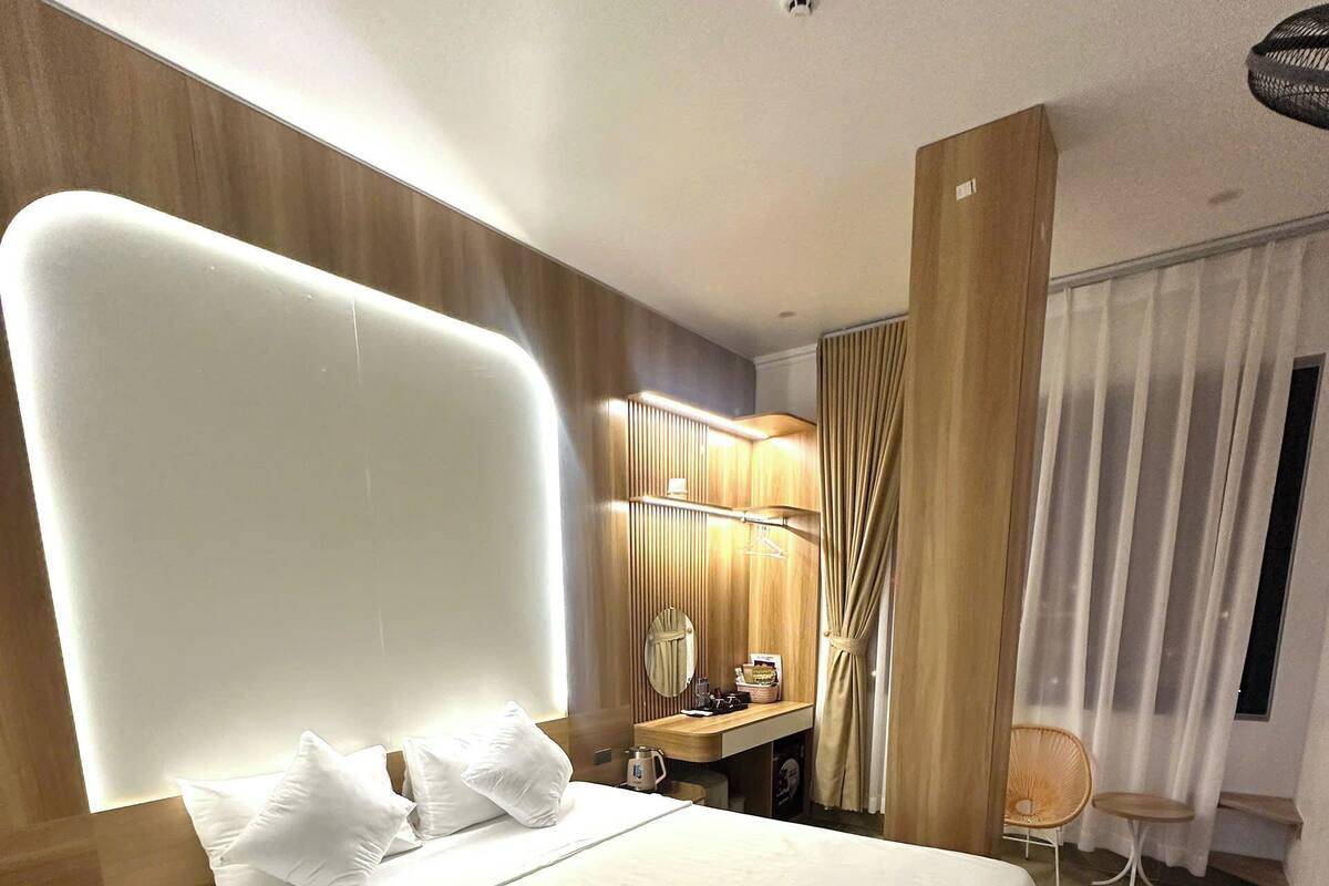 Una habitación de hotel moderna con una cama grande, un escritorio, una silla y un área de baño.