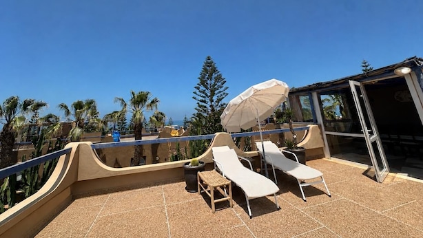 Una terrazza sul tetto con due lettini, un tavolo e un ombrellone.