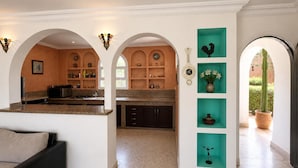 Una cucina moderna con ripiani in granito, forno integrato e zona pranzo con divano nero.