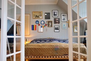 A bedroom with a bed, a wooden bench, a wall with framed pictures, and a door. - Spacious penthouse in the heart of Reykjavik city (Reykjavík)