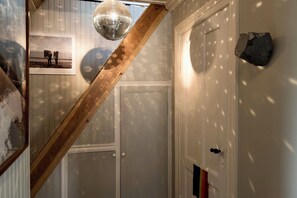 A staircase with a wooden handrail, a disco ball, a door with a stone accent, and a framed photo on the wall. - Spacious penthouse in the heart of Reykjavik city (Reykjavík)
