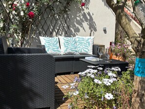 A wicker outdoor seating area with a table, cushions, and a potted plant. - Provencal house with large swimming pool. Close to the sea! (La Garde)