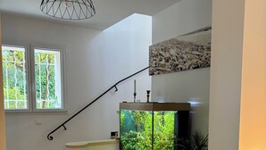 En trappe med et akvarium, et træskab, en potteplante og et billede hængt på væggen.