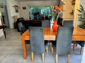 A dining area with a wooden table, grey upholstered chairs, and a bright orange vase with flowers. - Provencal house with large swimming pool. Close to the sea! (La Garde)