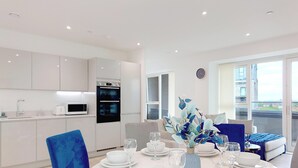 A modern kitchen with white cabinets, a built-in oven, and a microwave. - Deluxe Serviced Three Bedroom Apartment (London)