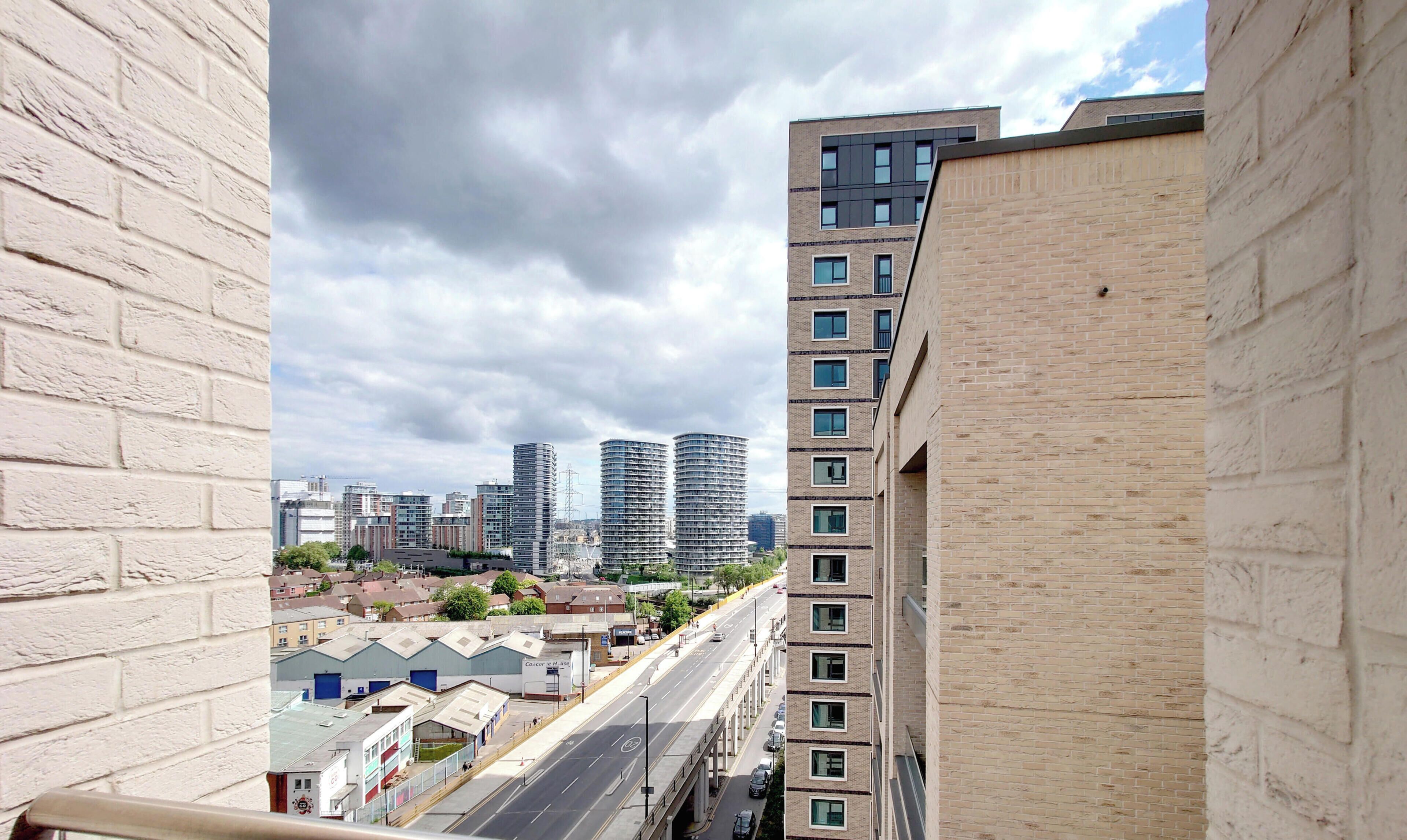 A high-rise building with a view of a cityscape, including other tall buildings and a road with vehicles.