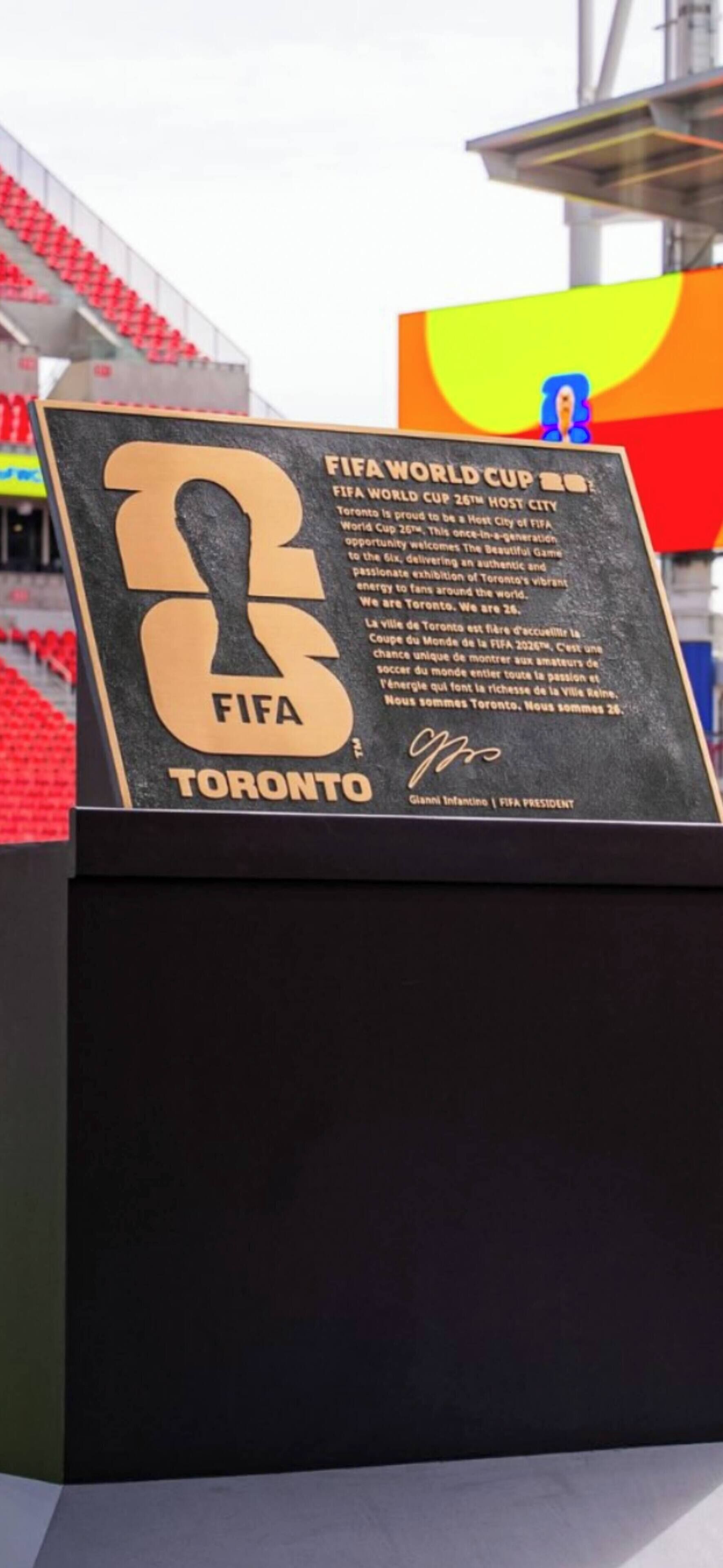 Une plaque noire avec une inscription dorée indiquant : « Toronto, ville hôte de la 26e Coupe du monde de la FIFA », ainsi qu’une signature.