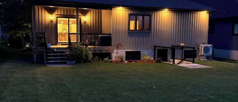 A modern house with a well-maintained lawn, a porch with outdoor seating, and a visible garage.