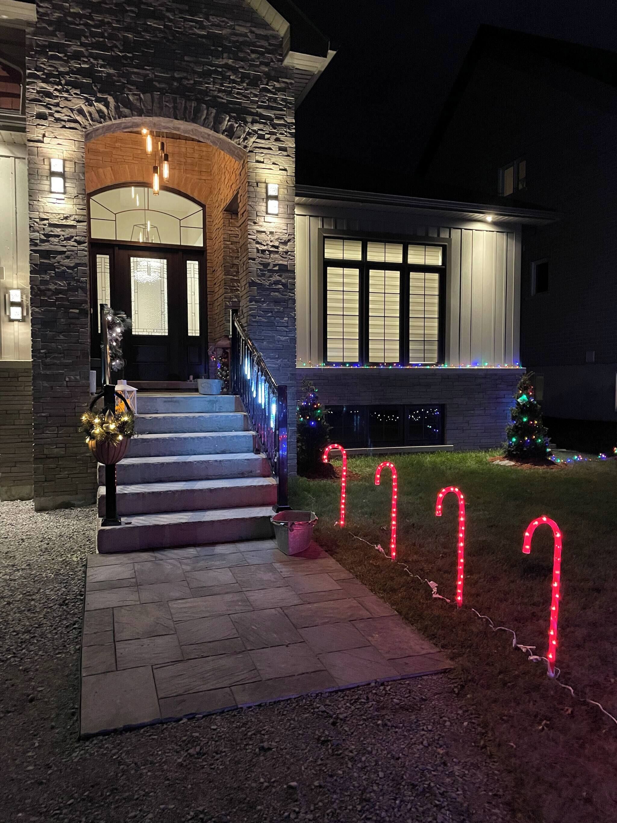 A house with a stone facade, a staircase leading to the entrance, and Christmas lights.